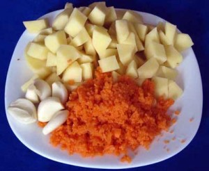 Нарезанный кубиками картофель тертая морковь очищенный чеснок