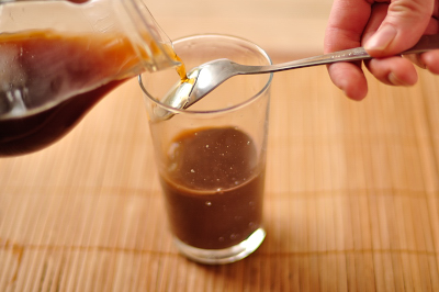 По тыльной стороне ложки наливается кофе в стакан с шоколадом