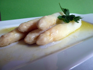 Отваренная белая спаржа со сливочным маслом и зеленью на тарелке