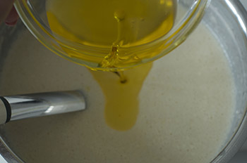 Наливаем растопленное сливочное масло в набухшее тесто из муки молока яиц сахара и соли