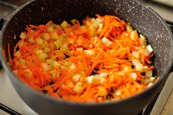 Мелкопорезанные лук морковь и сельдерей жарятся на оливковом масле в сотейнике