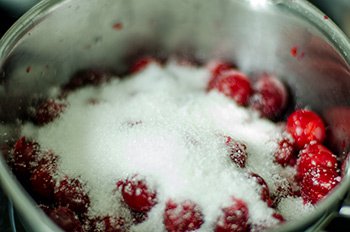 Помытая и очищенная вишня засыпана сахаром в кастрюле