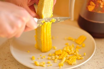 С кукурузы срезаются зерна для замораживания острым ножом