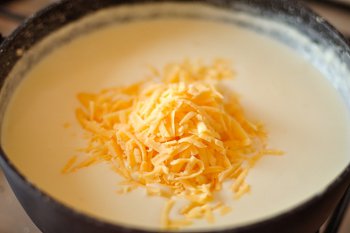 В соус бешамель добавлен тертый сыр для приготовления лазаньи
