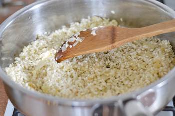 Сухой рис обжаривается на сковороде с луком и чесноком