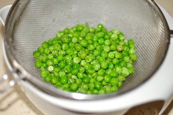 Замороженный зеленый горошек в дуршлаге для приготовления котлет