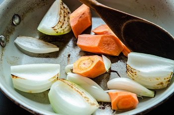 Крупно порезанные лук и морковь обжариваются на сухой сковороде без добавления масла
