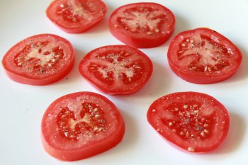 Кусочки помидоров порезанные дольками и присыпанные солью и перцем