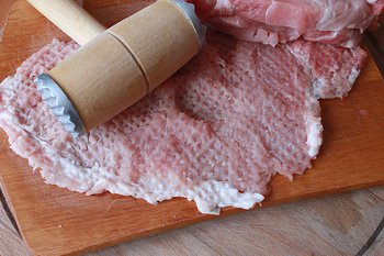 Обработанный кусок свиной корейки отбивается молотком