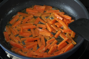 Очищенная и порезанная соломкой морковь обжаривается на сливочном масле