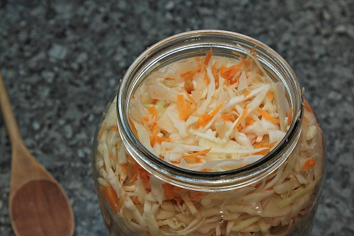 Натертая морковь, нарезанная капуста и чеснок в банке - маринованная капуста
