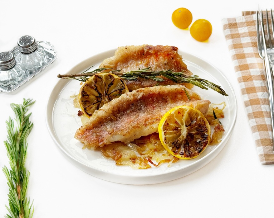 Жареный морской окунь с луком на сковороде